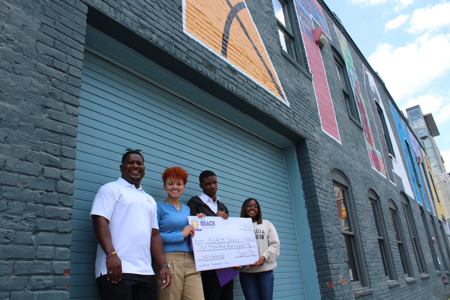 Brian Q. Lee with REACH scholarship recipients holding an oversized check